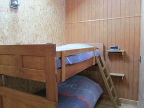 A small, compact room with a bunk bed and a desk.