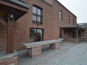 A brick building with a balcony, a table, and a covered seating area.