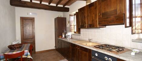 A kitchen with wooden cabinets, a gas stove, a sink, and a dining area with a table and chairs.