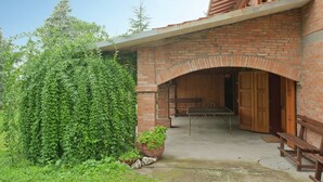 Ein Backsteinhaus mit Bogenportal, einer Holzbank und einem Tisch vor der Fassade.