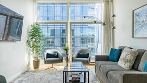 A modern living room with a grey sofa, two armchairs, a glass coffee table, and a large window with a city view. - Walk to everything: Pike Place Penthouse, Seattle (Seattle)
