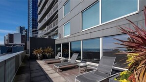A rooftop terrace with sun loungers, potted plants, and a view of the city skyline. - Walk to everything: Pike Place Penthouse, Seattle (Seattle)