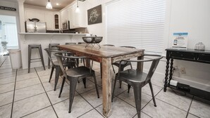 A modern kitchen with white cabinets, a wooden dining table, and metal chairs.