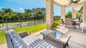 Un balcon avec un canapé, une table en verre et un coin repas comprenant des chaises et une table.