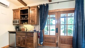 A kitchen with wooden cabinets, a microwave, and a coffee machine. - The Bodega w/personal hot tub & fireplace (Fredericksburg)