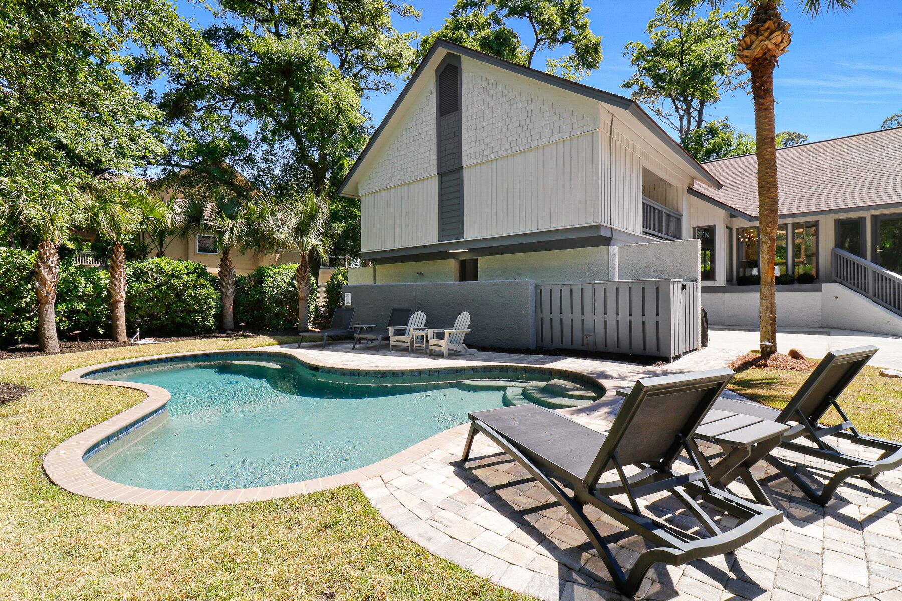 Ein Haus mit Swimmingpool, Außenbereich mit Sitzgelegenheit und einem eingezäunten Deck.
