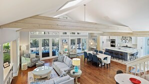 A spacious living area with a high ceiling, large windows, and a kitchen area. - Newly Renovated 3rd Row Palmetto Dunes home with pool on beach path! (Hilton Head Island)