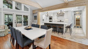 A spacious kitchen with a central island, bar stools, and a dining area with a large table and chairs. - Newly Renovated 3rd Row Palmetto Dunes home with pool on beach path! (Hilton Head Island)