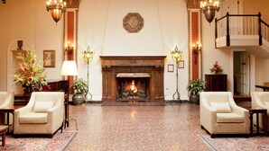 Eine beeindruckende Lobby mit Kamin, zwei Sesseln, einem großen Teppich und einer Treppe.