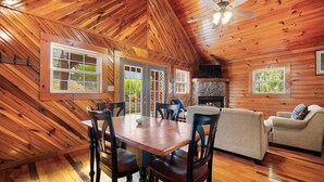Un intérieur en bois comprenant une table à manger, des chaises, un canapé et une cheminée.