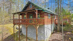 Une cabane en bois dotée d’un balcon, entourée d’arbres.
