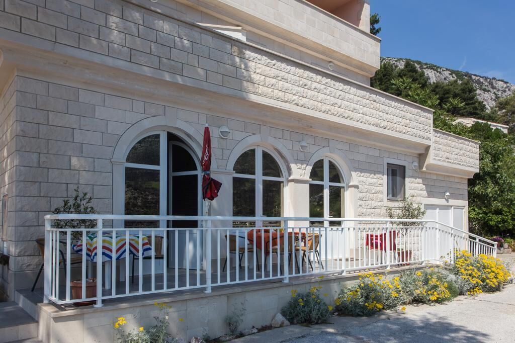 Un bâtiment doté d’une façade en pierre, de fenêtres en arc de cercle et d’une balustrade blanche.