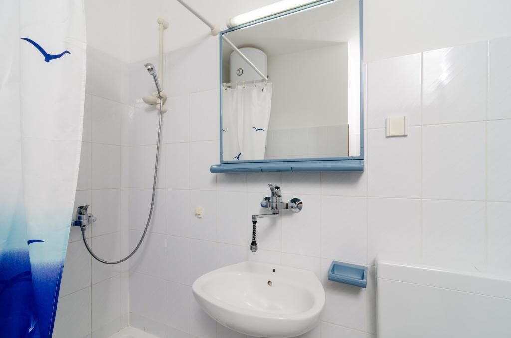A bathroom with a white sink, a mirror, and a shower.
