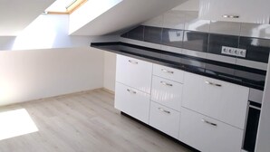 Eine moderne Küche mit weißen Schränken, einer schwarzen Arbeitsplatte und einem Oberlicht.