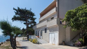 Ein zweistöckiges Gebäude mit einer Stein-Fassade, einem Balkon und einer Garage.