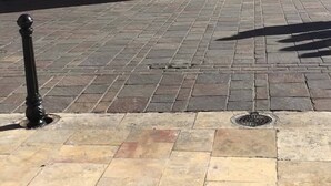 Una plaza pavimentada con un edificio que tiene una gran entrada en arco y una ventana con barrotes.