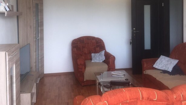 Una sala de estar con un aparador de madera, un sillón rojo, un sofá y una mesa de centro de vidrio.
