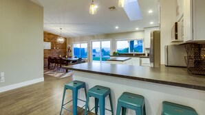 A modern kitchen with a large island, bar stools, and pendant lighting. - Spacious home with incredible backyard views (San Diego)