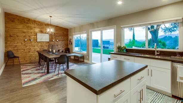 A modern kitchen with a large island, white cabinets, and a view of the outdoors. - Spacious home with incredible backyard views (San Diego)