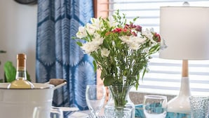 Una mesa de comedor dispuesta con platos, vasos y un jarrón de flores.