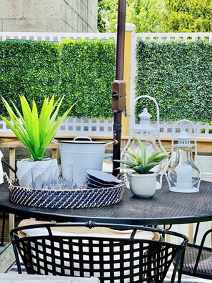 A table set outdoors with a white fence and green hedge in the background. - Last Second Deal ! Steps to Ocean & Black Point and by Scarborough Beach ! (Narragansett)
