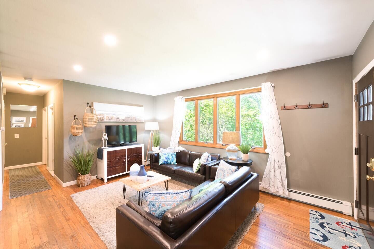 A living room with a sofa, a TV, and a window with curtains.