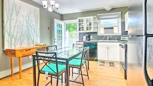 A modern kitchen with a dining area, featuring a glass table, chairs, a wooden bench, and a chandelier. - Fully stocked vacation home with large private yard, decks and BBQ gas grill & 1 mile to Narragansett Beach ! (Narragansett)