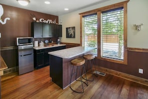 Una cocina moderna con una isla central, taburetes de bar, microondas y un letrero de café.