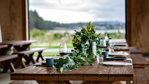 A wooden table set for dining with a view of a lake and hills. - Bay Point Landing (Coos Bay)