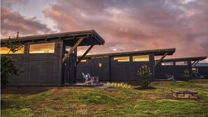A modern building with a flat roof and large windows, surrounded by a grassy area and a small pond. - Bay Point Landing (Coos Bay)