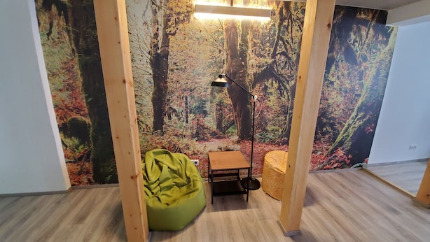 A room with a forest-themed mural, a green bean bag chair, a small wooden table, and a floor lamp. - Vacation apartment "Pfalz" - centrally located in Grünstadt (Grünstadt)