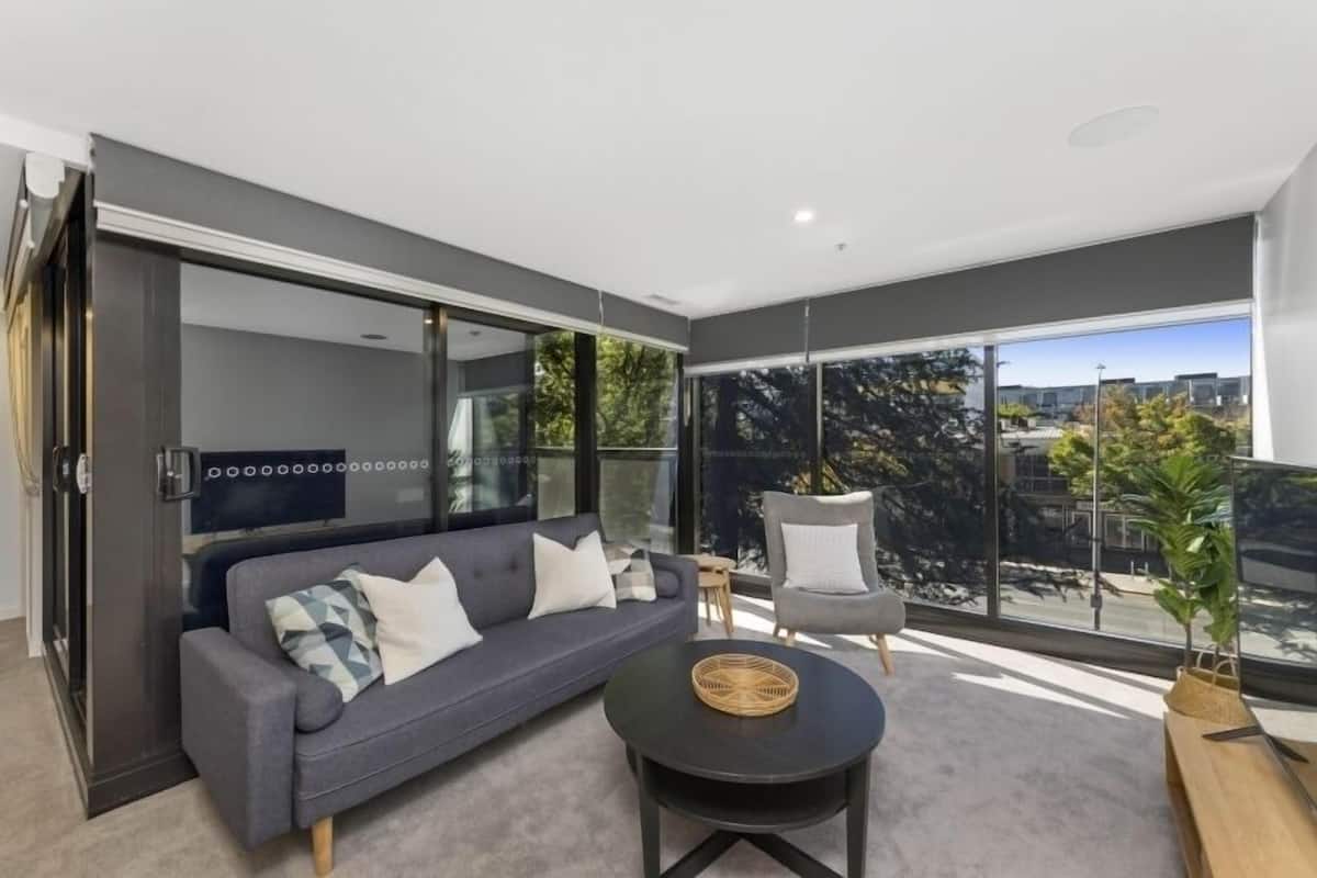 A modern living room with a grey sofa, a round coffee table, and a grey armchair.