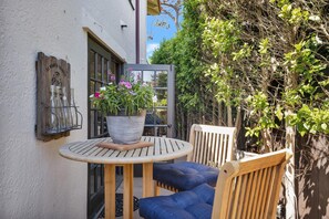 Une table en bois avec un pot de fleurs, un banc et un luminaire fixé au mur.
