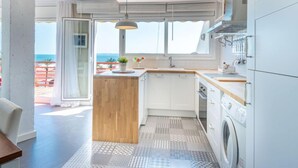Una cocina moderna con una isla de madera, armarios blancos y vista al mar.