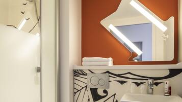 Une salle de bain avec une douche, un lavabo et un miroir.