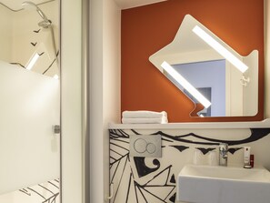 Une salle de bain avec une douche, un lavabo et un miroir.