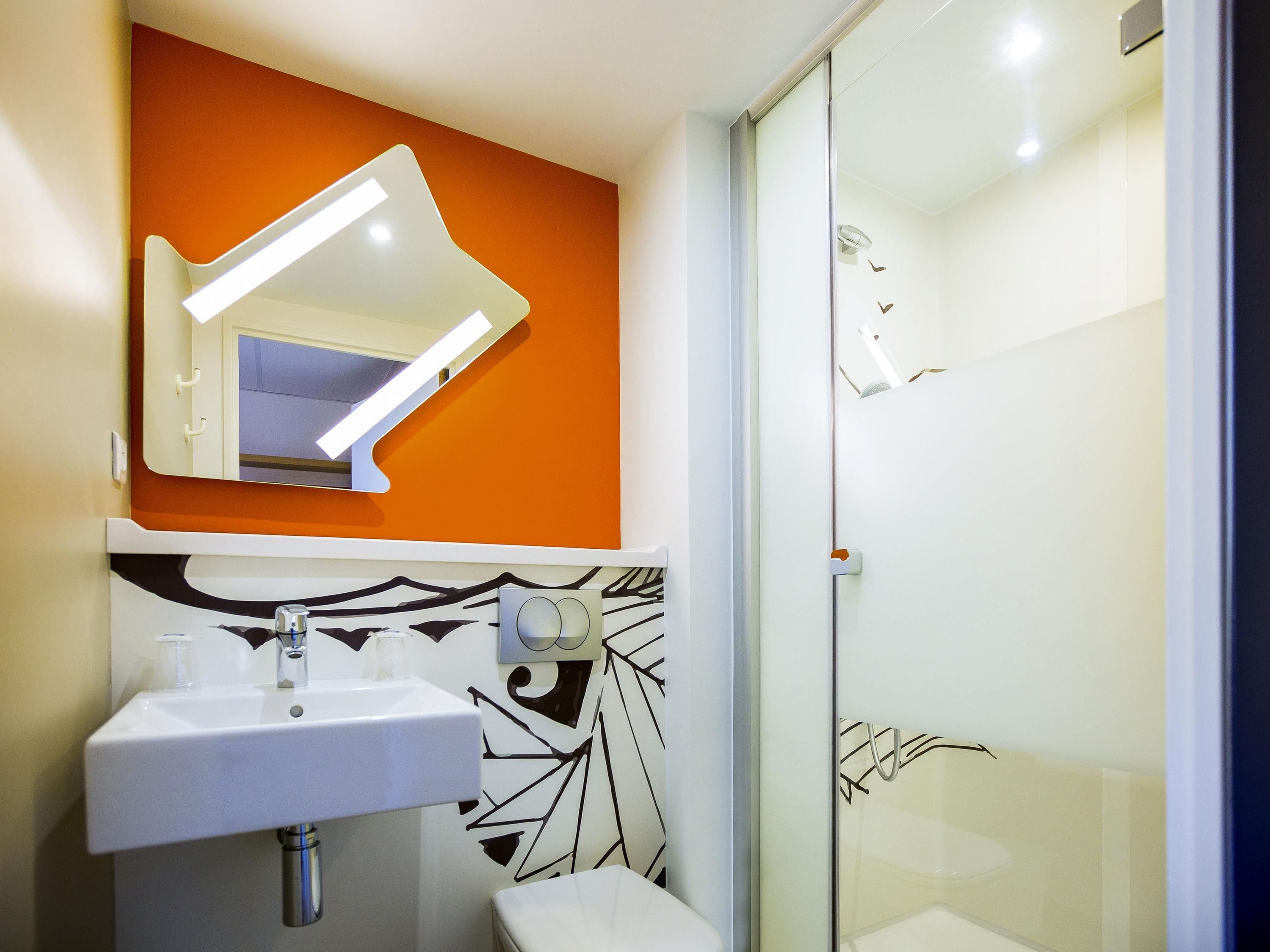 Een moderne badkamer met een witte wastafel, spiegel en douche.
