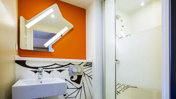 Een moderne badkamer met een witte wastafel, spiegel en douche.