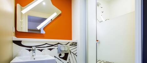 A modern bathroom with a white sink, mirror, and shower.