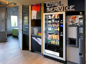 A vending machine area with a 'COOL SERVICE' sign, a beverage dispenser, and a snack vending machine. - ibis budget Beauvais Aeroport (Tille)
