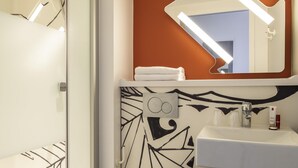 Ein Badezimmer mit Dusche, Waschbecken und Spiegel.
