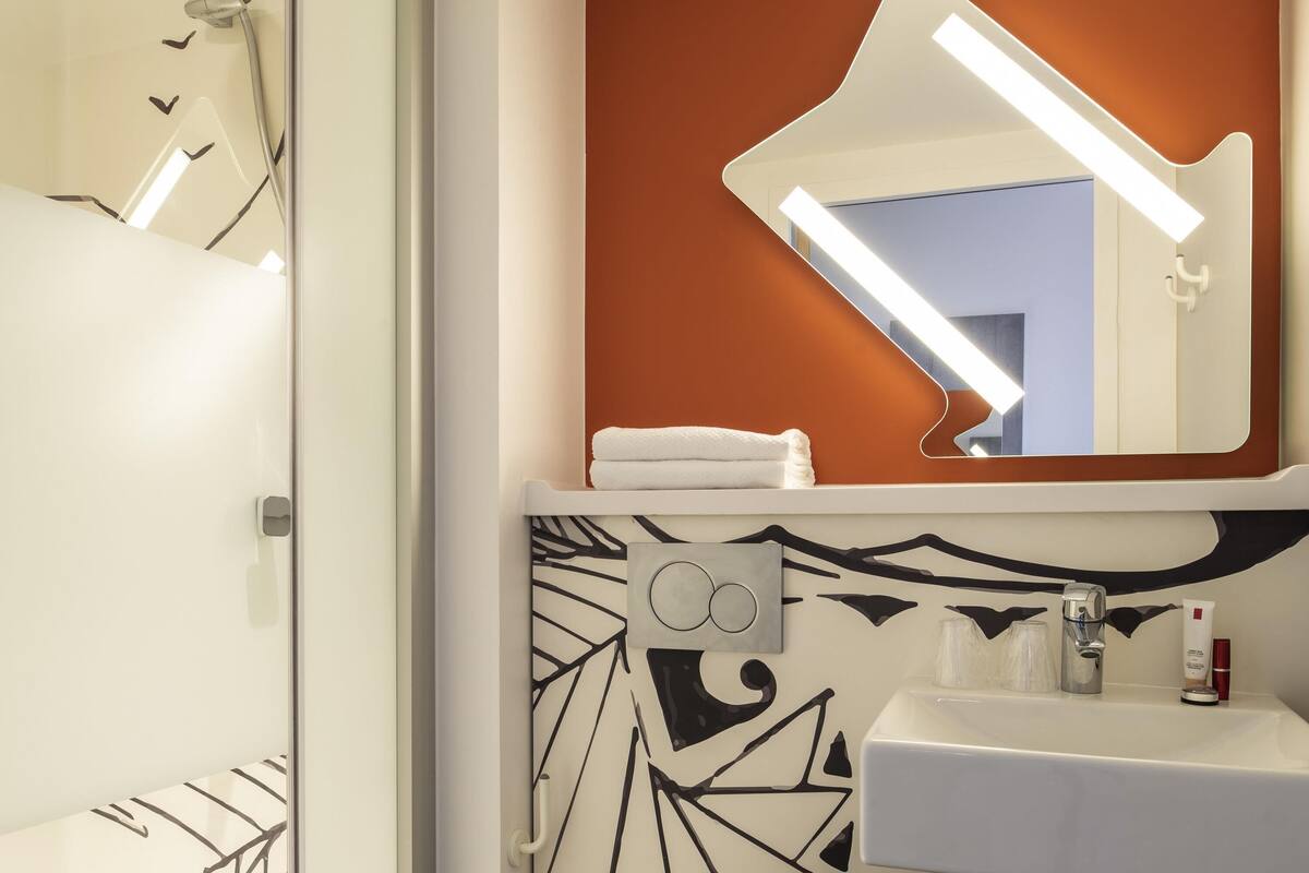 Ein Badezimmer mit Dusche, Waschbecken und Spiegel.