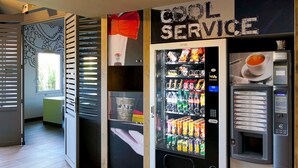 Un espace équipé de distributeurs automatiques, avec une pancarte indiquant « SERVICE RAPIDE », un distributeur de boissons et un distributeur d’en-cas.