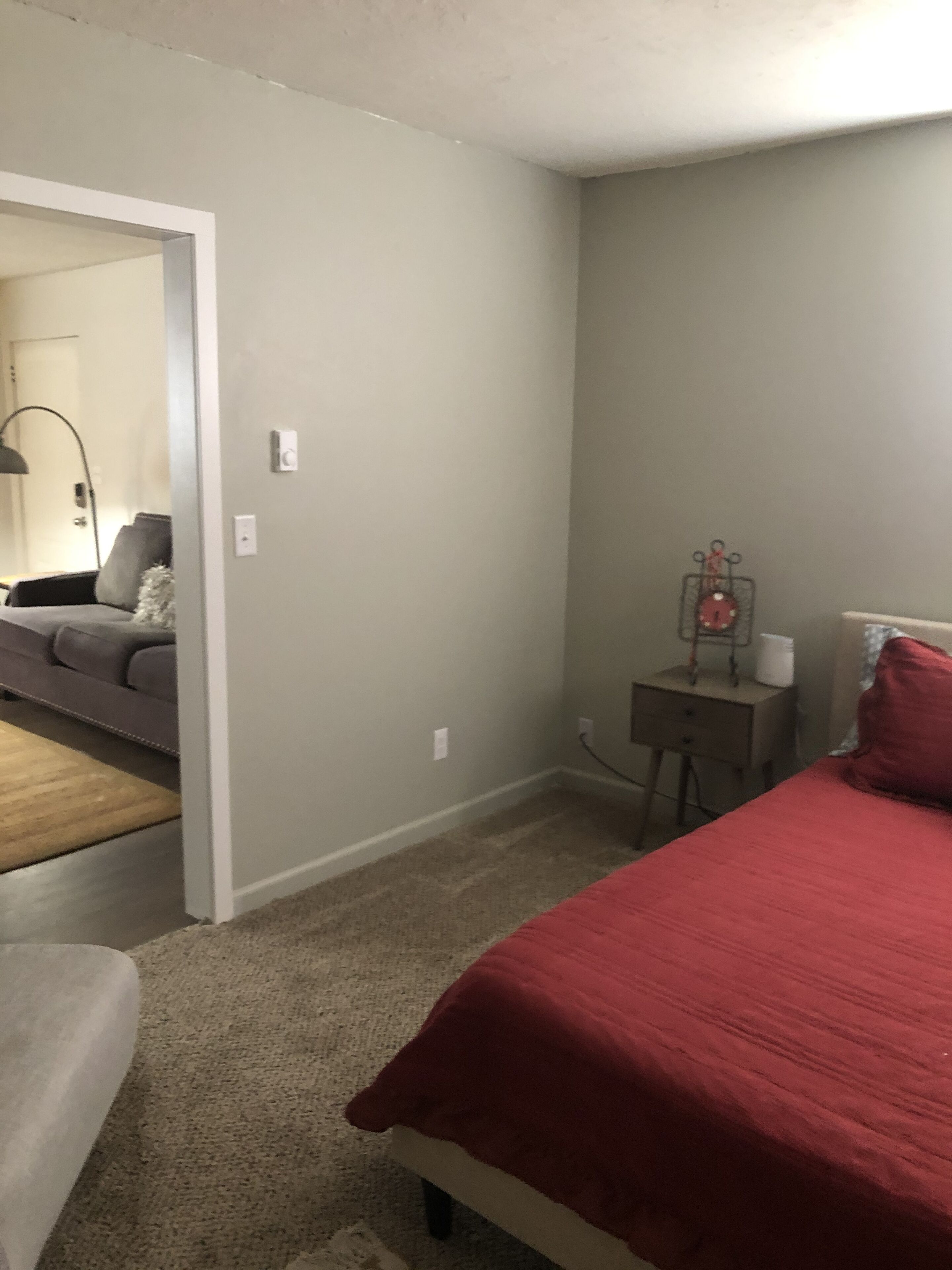 A bedroom with a bed, a nightstand, a lamp, and a dresser.