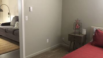 A bedroom with a bed, a nightstand, a lamp, and a dresser.