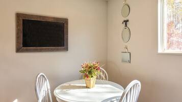 Un comedor con una mesa redonda, dos sillas, una planta en maceta y espejos en la pared.