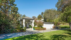 A house with a covered porch, surrounded by well-maintained lawns and trees. - Beautiful Napa Valley Home on Golf Course -  Perfect Wine Country Retreat (Napa)
