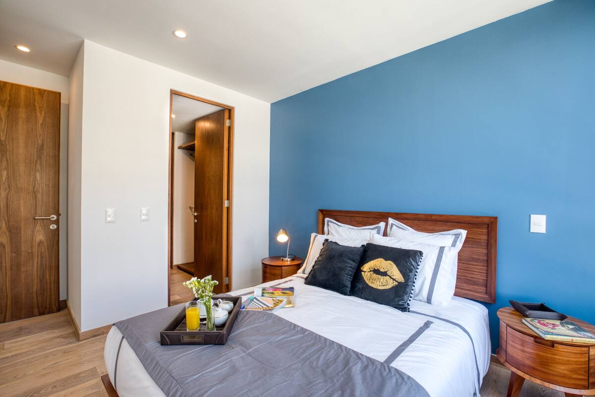 A hotel room with a bed, bedside table, and a wooden door.