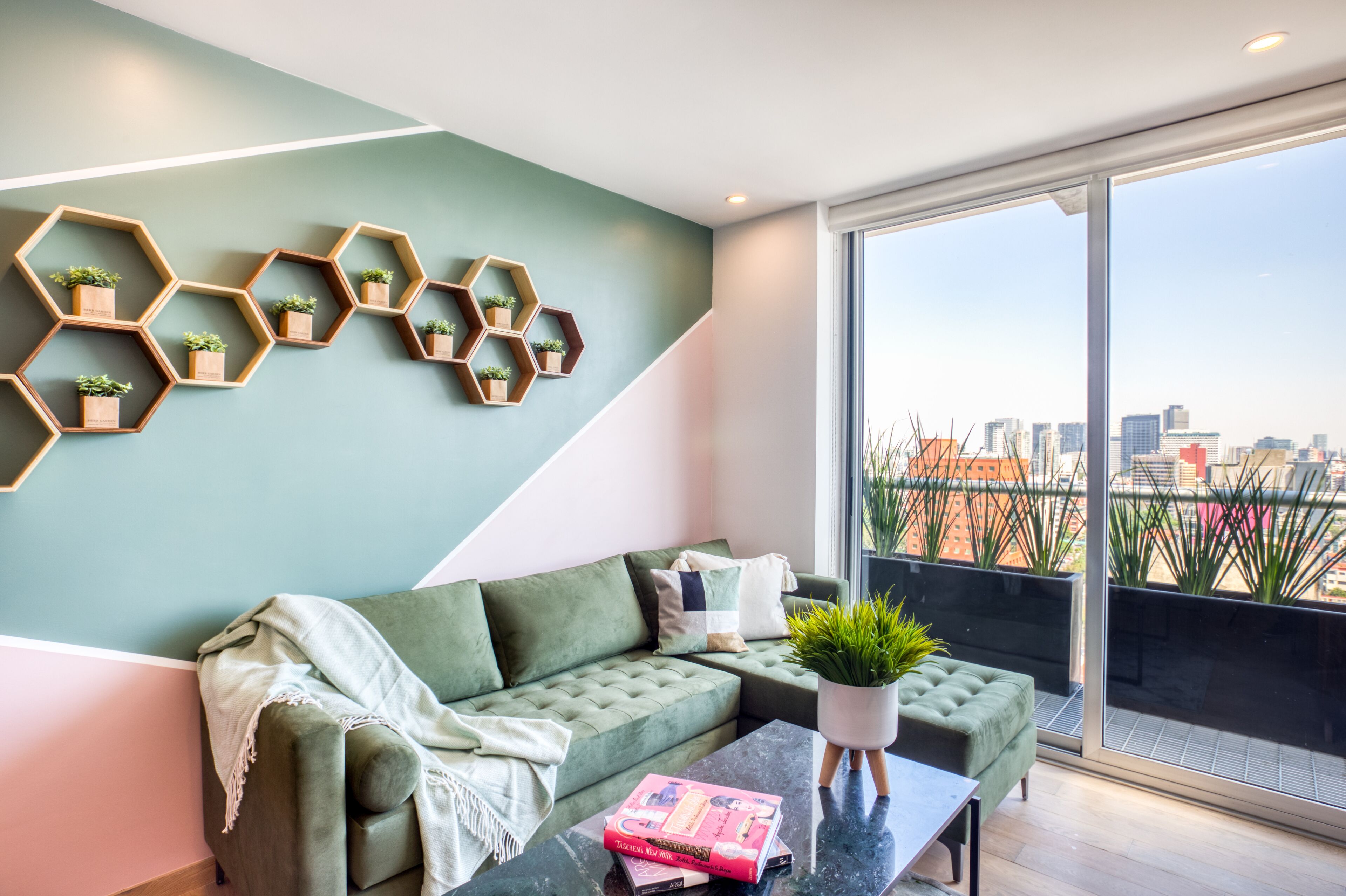 A modern living room with a green sofa, a coffee table, and hexagonal shelves with plants.