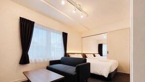 Habitación de hotel con cama, sofá, una mesita y un espejo grande.